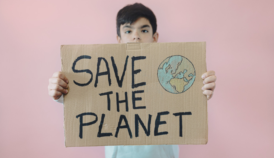 Young teenage boy holding a cardboard sign that says "save the planet."