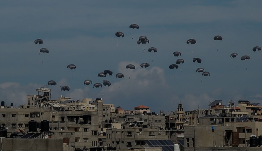 Parachutes filled with aid boxes float down as planes drop humanitarian aid around various regions in the northern Gaza, Gaza on March 09, 2024. Photo by Omar Qattaa/Anadolu via Getty Images.