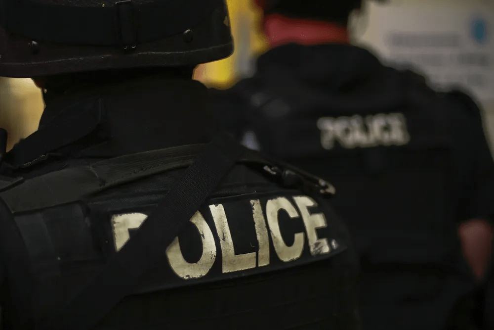 The back of a police officer's black tactical uniform with the word "police" spelled out in capital letters